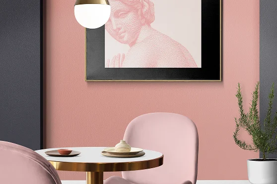 Modern interieur met pastelroze stoelen, ronde tafel, hanglamp en ingelijste wanddecoratie die een stijlvolle en gezellige sfeer creëren.